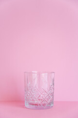 empty and transparent faceted glass on pink background.