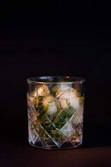cool faceted glass with rum and ice cubes isolated on black.
