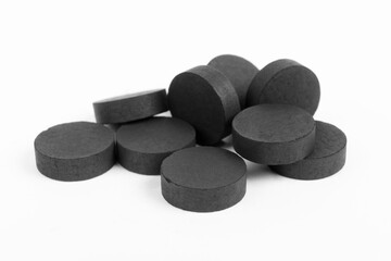 Activated charcoal tablets on a white background in the studio.