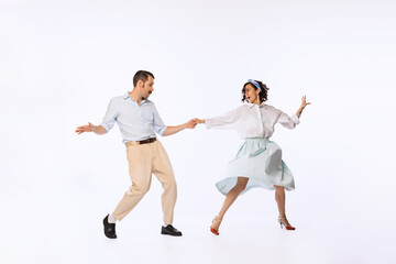 Portrait of young beautiful couple, man and woman, dancing swing isolated over white studio...