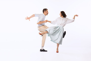 Portrait of young cheerful couple, man and woman, dancing boogie woogie isolated over white studio...