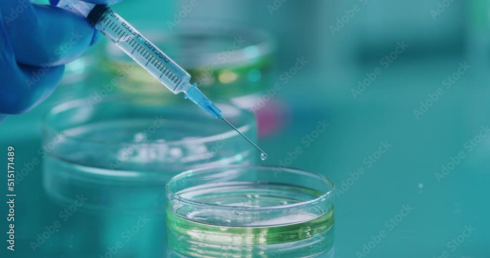 Poster closeup of a scientist hand holding a syringe with a needle and glass plate or petri dish in a medic