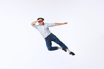 Fototapeta na wymiar Portrait of stylish young man in retro outfit dancing, posing isolated over white studio background