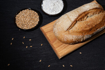 Homemade bread with grains and wheat flour on dark background
