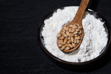 Loaf with grains of wheat in flour. On dark concrete background