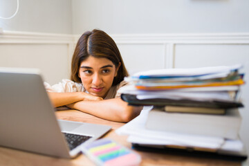 Stressed woman looking at a lot of work papers at her desk