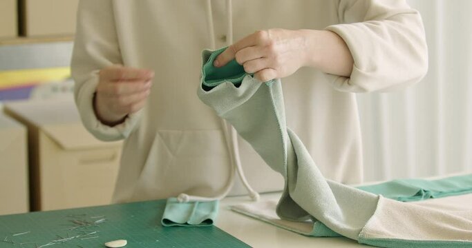 Skilled worker putting the pin to the fabric while preparing future sweatshirt