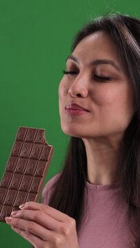 Young woman bites into a bar of chocolate - studio shooting