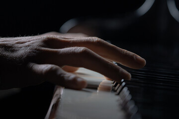 Talented pianist plays classical melody on piano in the dark. Detailed close up shot of a mans...