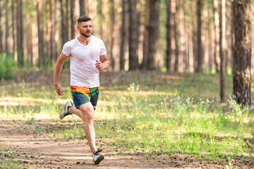 Running man. Male runner jogging at the park. Guy training outdoors. Exercising on forest path. Healthy, fitness, wellness lifestyle. Sport, cardio, workout concept