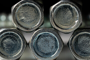 Heads of metal bolts on an isolated black background. Stainless steel hexagon bolts for screwing, fastening, fixing. A set of mettalik construction bolts for a hardware store and furnitures. Close up.