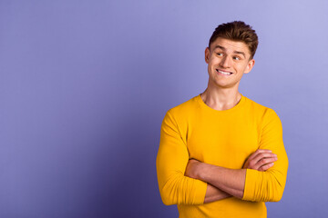 Photo of young cheerful guy crossed hands look empty space wonder dream isolated over violet color...