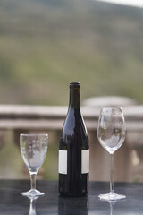 A bottle of wine and two glasses on the table at the balcony of the restaurant. High quality photo
