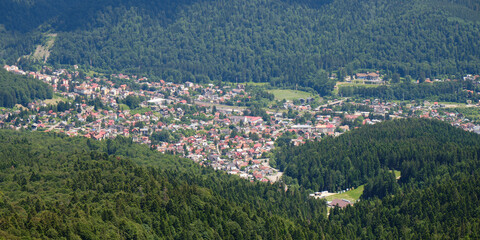 Fototapeta na wymiar Aerial panorama of Busteni village in Prahova Valley, surrounded by forest, a popular outdoor destination in Romania.