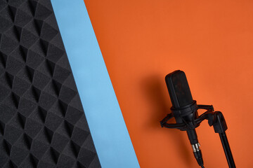 Microphone on double color blue and orange background and acoustic foam panel