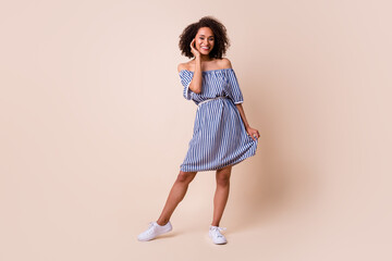 Full length photo of pretty sweet lady wear striped outfit smiling walking isolated beige color...