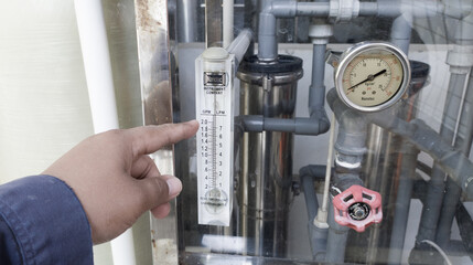 A man's hand is showing a glass measuring the flow of water that enters the clean water filter system,Scale of measurment glass. 