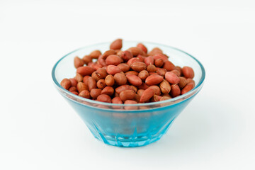 Brown peanuts in a plate on a white background.