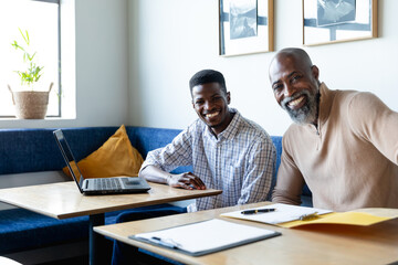 Obraz premium Portrait of smiling african american businessmen at desk in creative office