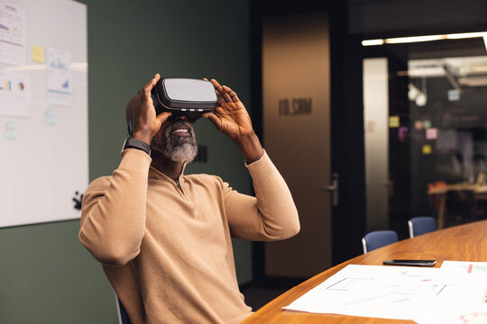 Mature african american businessman using virtual reality simulator at office - Powered by Adobe