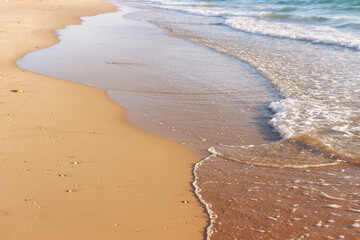 Sea waves and warm sunset light, calm and relaxing sandy beach