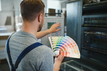 Funny portrait of typographer standing with color swatches at the printing manufacturing - obrazy, fototapety, plakaty