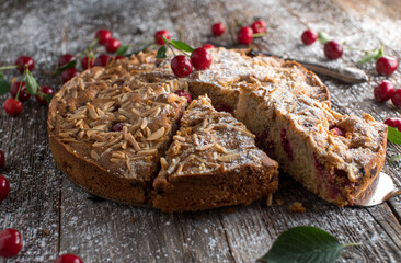 Cherry cake with almond topping on wooden table