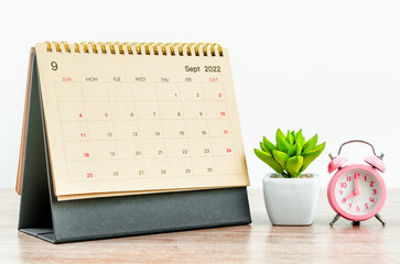 The September 2022 green Desk calendar with pink alarm clock on wooden table. - obrazy, fototapety, plakaty