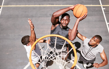 Basketball players blocking a player from dunking a ball into net to score points during a match on...