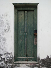 Antique green wooden door on the white old wall