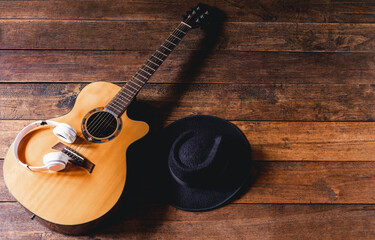 Top view acoustic guitars with earphones and hipster hats on old wooden background.Flat lay