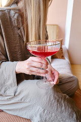 A glass of red wine, champagne or a cocktail in the hands of a girl relaxing. Tasting of alcoholic beverages. Summer rest. Romantic evening aperitif. Close-up of a glass of wine
