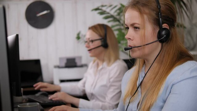 Smiling friendly female call-center agent with headset working on support hotline in the office.