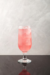 Grapefruit cocktail with ice cubes in tall drinking glass. Pink refreshing summer drink
