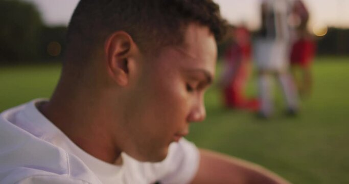 Video of sad biracial football player siting on field