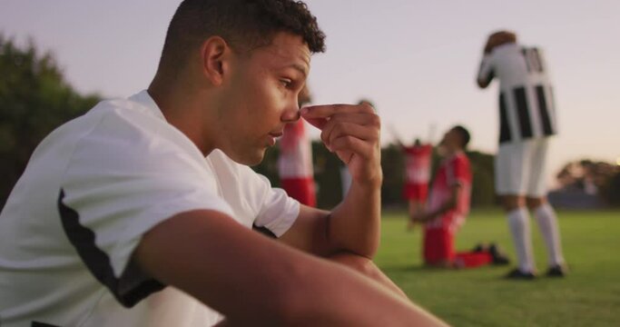 Video of sad biracial football player siting on field