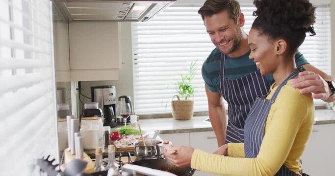 Video of happy diverse couple preparing meal, trying dish