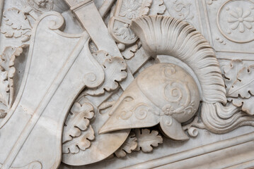 Close-up on ancient roman helmet carved in a decorated marble wall