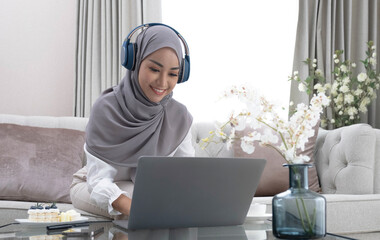 Online Tutoring. Young muslim woman teacher having video call with students, talking at laptop camera, sitting on couch at home