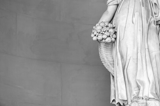 Black and white photo showing in detail the hand of a marble classic statue holding a cornucopia full of fruits