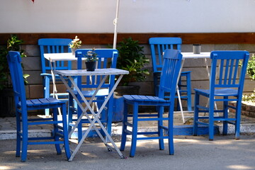 Blue dining table and chairs in front of the Mediterranean house.