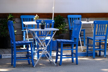 Blue dining table and chairs in front of the Mediterranean house.