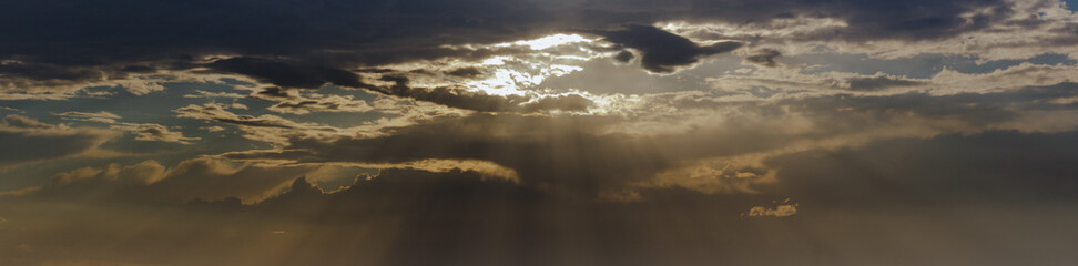 Golden sun rays breaking through the clouds in the sky.