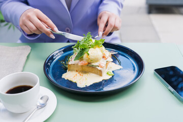 Close-up breakfast of poached eggs and toast. Young woman having breakfast on the summer terrace