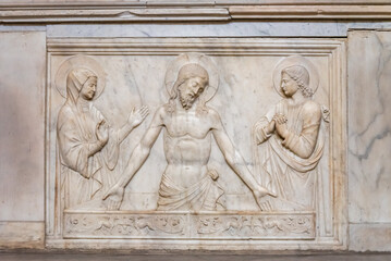 Religious scene carved in a marble wall inside a church in Napoli, showing Jesus Christ, Virgin Mary and a catholic saint reunited.