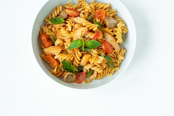 Close up Tasty Gourmet Spicy Pasta with Tomato and Herbs on a White Plate, Served on Top of a white wooden  Table.