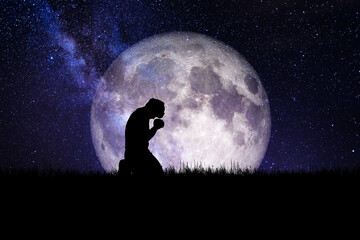 Man sitting and praying to God against a beautiful moon backdrop. element of the picture is decorated by NASA