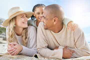 Fototapeta premium Smiling married couple bonding with daughter on the beach. Cute adorable little girl embracing and lying on her mother and father outside. Happy husband and wife enjoying free time with their child