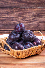 Black plum on wood background. A pile of black plums in a basket. close up