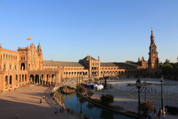 Fototapeta premium Seville, Spain, September 11, 2021: The Spanish Steps in Seville or 'Plaza de España', where the main building of the Ibero-American Exhibition of 1929 was built. Spanish flag at sunset.